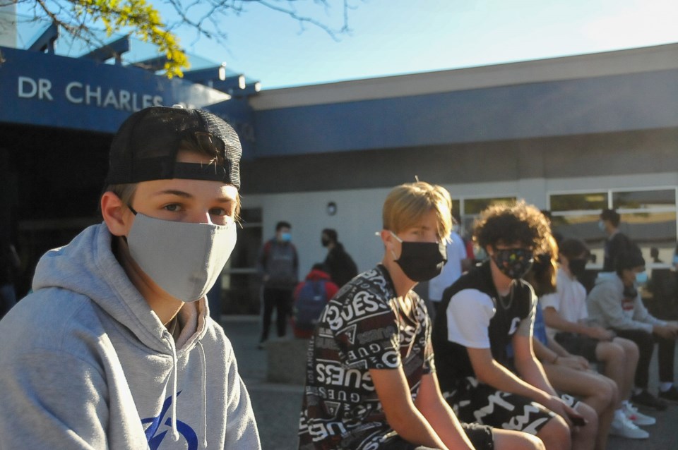 Grade 9 and 10 students wait apart on the first day of school outside Dr. Charles Best secondary in