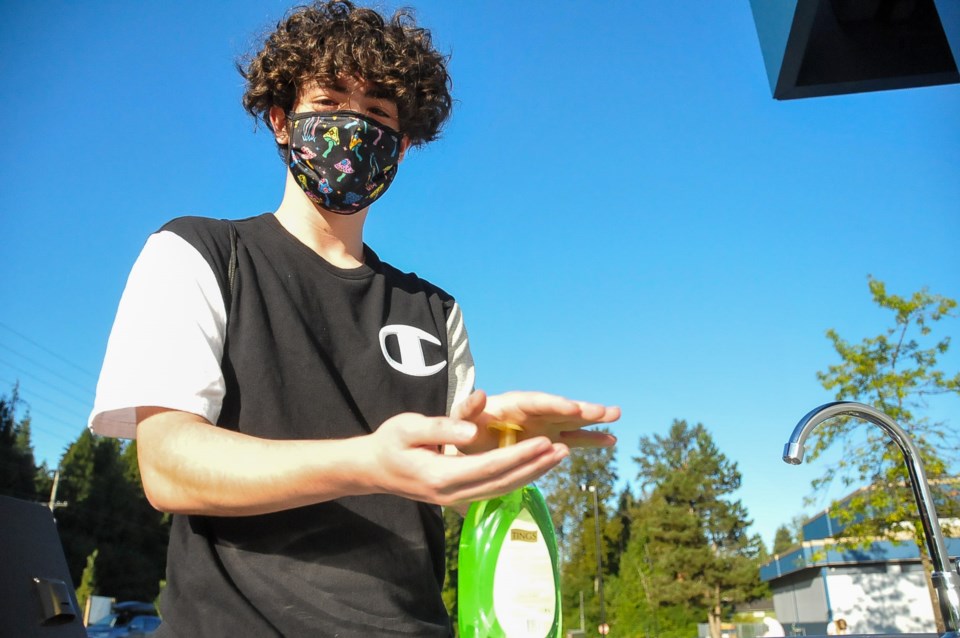 Coquitlam student Tyson Symons washes his hands at a washing station outside Dr. Charles Best second