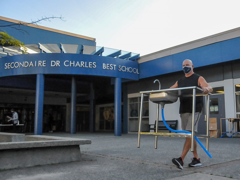 Caretaker Dave Leblanc sets up portable handwashing stations around Dr. Charles Best secondary in Co