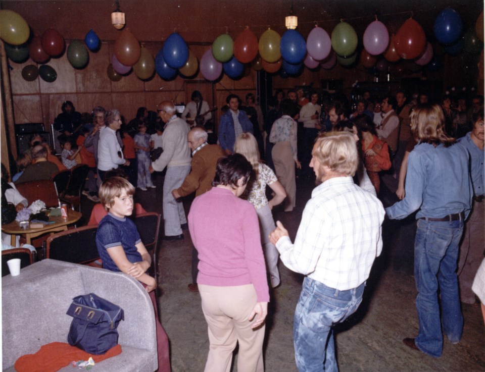 People dancing in a hall with balloons hanging from the ceiling