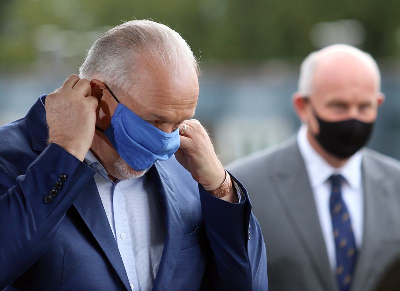 BC NDP leader John Horgan pulls on a mask under the watchful gaze of Port Coquitlam candidate Mike F