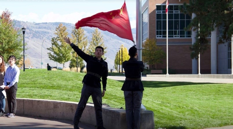 Two Thompson Rivers University students dressed in military-style Chinese uniforms and raised China’