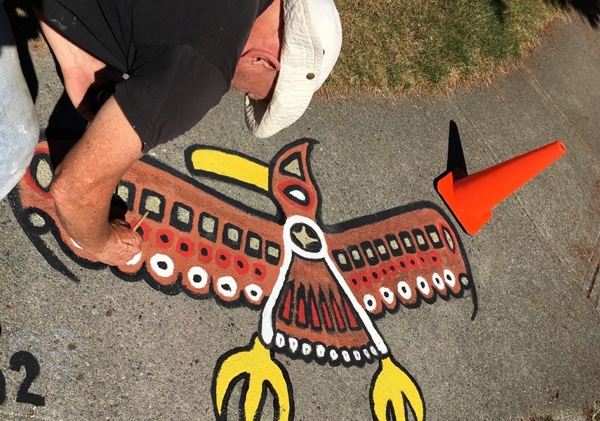 A street artist paints a Thunderbird. A North Vancouver couple has been filling their street corner with artwork since the pandemic began. photo Bren.Vancouver