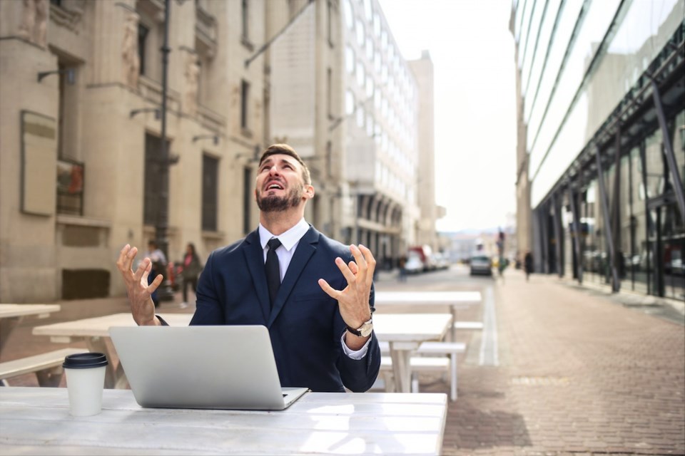 Man looking up at the sky in distress with a computer in front of him