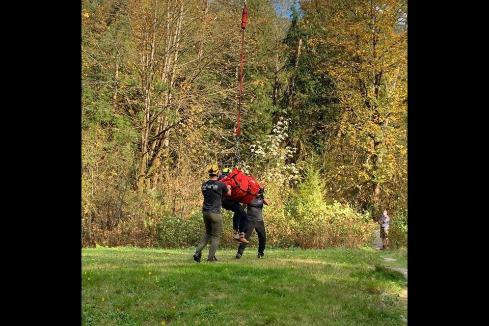 Rescuers guide an injured hiker into the grass after she was rescued by helicopter longline Tuesday