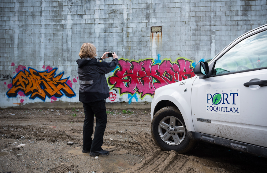 Port Coquitlam bylaw officer examines graffiti in the city. New fines are in the works for property owners who don’t clean up their properties.