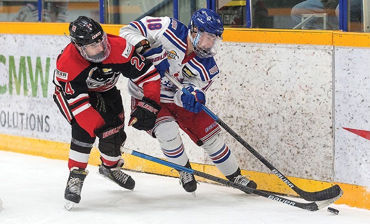 Spruce Kings winger Kolton Cousins moves the puck along the boards while being watched by Merritt Centennials winger Zack Dallazanna during Sunday's BCHL preseason game at Rolling Mix Concrete Arena.