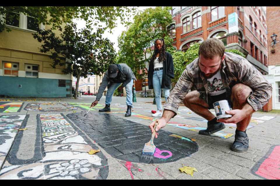 The City of Victoria has reached an agreement with artists who painted ACAB in a mural in Bastion Square. Ken Derival, left, Charity Williams and Rob Banks cover up part of the mural after the artists agreed to paint over the letters ACAB. ADRIAN LAM, TIMES COLONIST