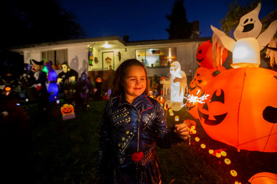 Seven-year-old Sophia Demedeiros lights a sparkler in front of an elaborate Halloween display Saturday on Teakwood Street in Saanich on Saturday, Oct. 31, 2020. DARREN STONE, TIMES COLONIST