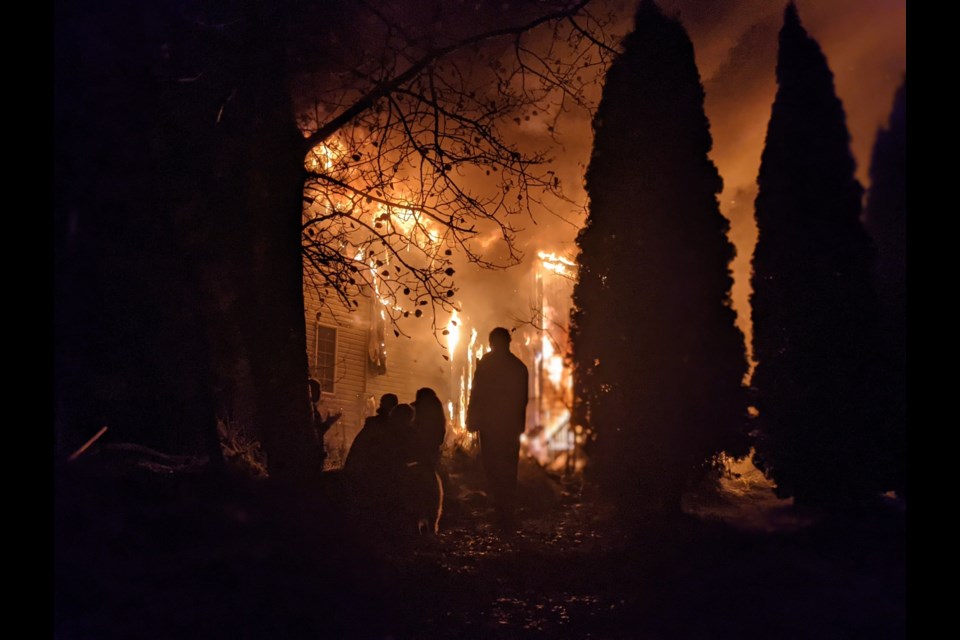 The occupants and neighbours of a Tabor Lake house that burned to the ground Sunday morning watch the flames destroy the building at 25 Rondane Cres.