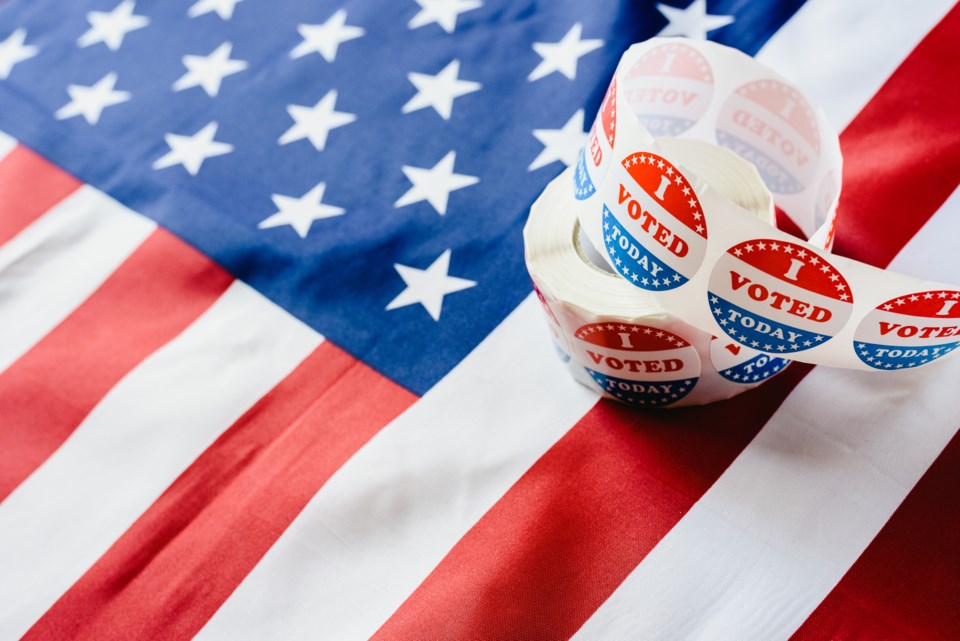 Stickers that say, 'I voted' are on top of the U.S. flag