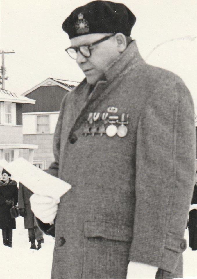 A man reading a speech in an overcoat with medals on his chest