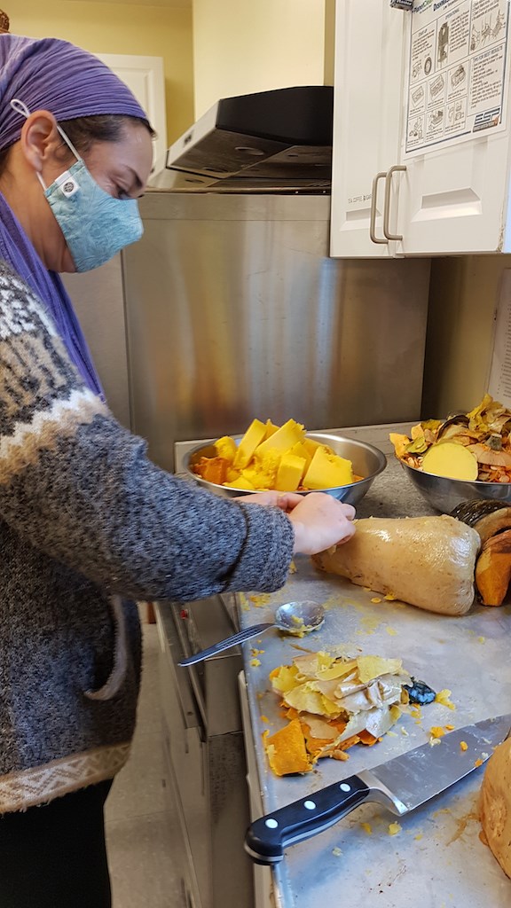 Meribeth peeling a squash in an industrial kitchen