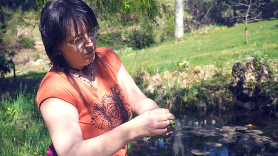 Emily beside a pond looking at vegetation