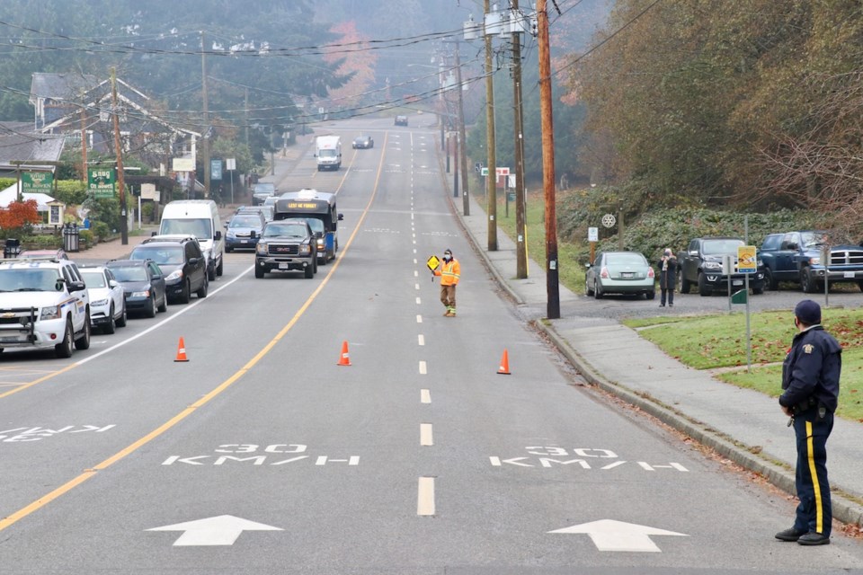 A road with cones and a man holding a 'slow sign'