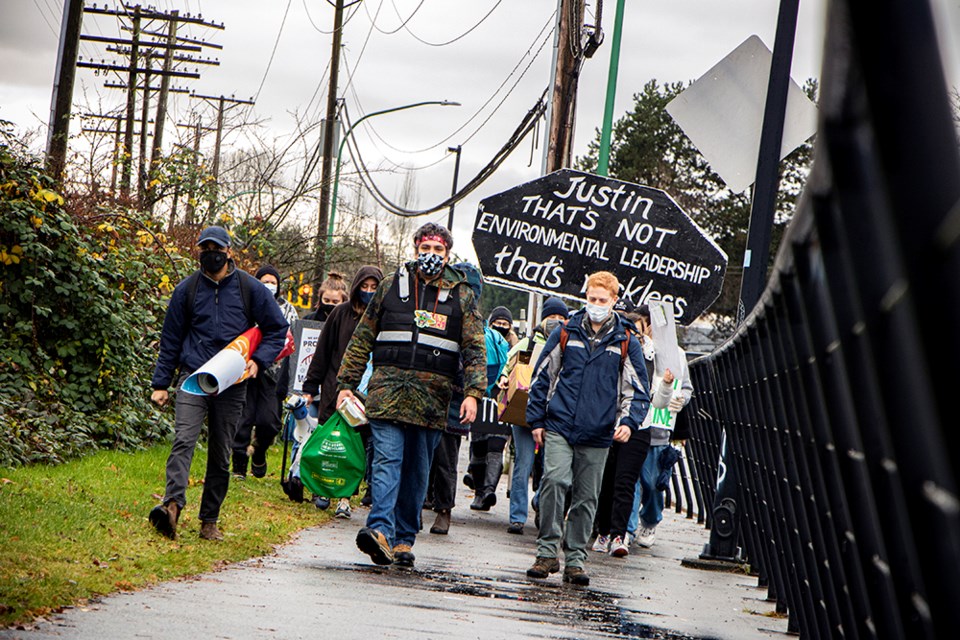 Demonstrators march down the sidewalk near Production Way, en route to block a railway in a protest against the Trans Mountain pipeline expansion.