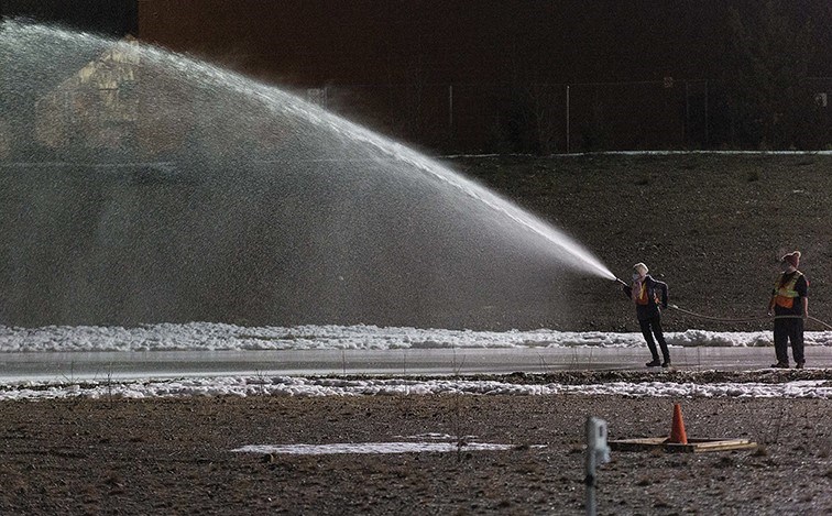 Volunteer flooding crew members shoot water from a high-pressure hose on the 400-metre Exhibition Park ice oval. The rink should be ready for skaters by next weekend.