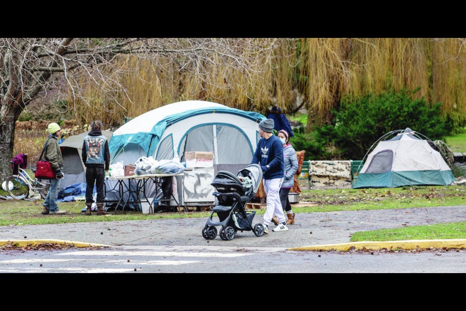 Park visitors pass a homeless camp in Beacon Hill Park on Wednesday. DARREN STONE, TIMES COLONIST