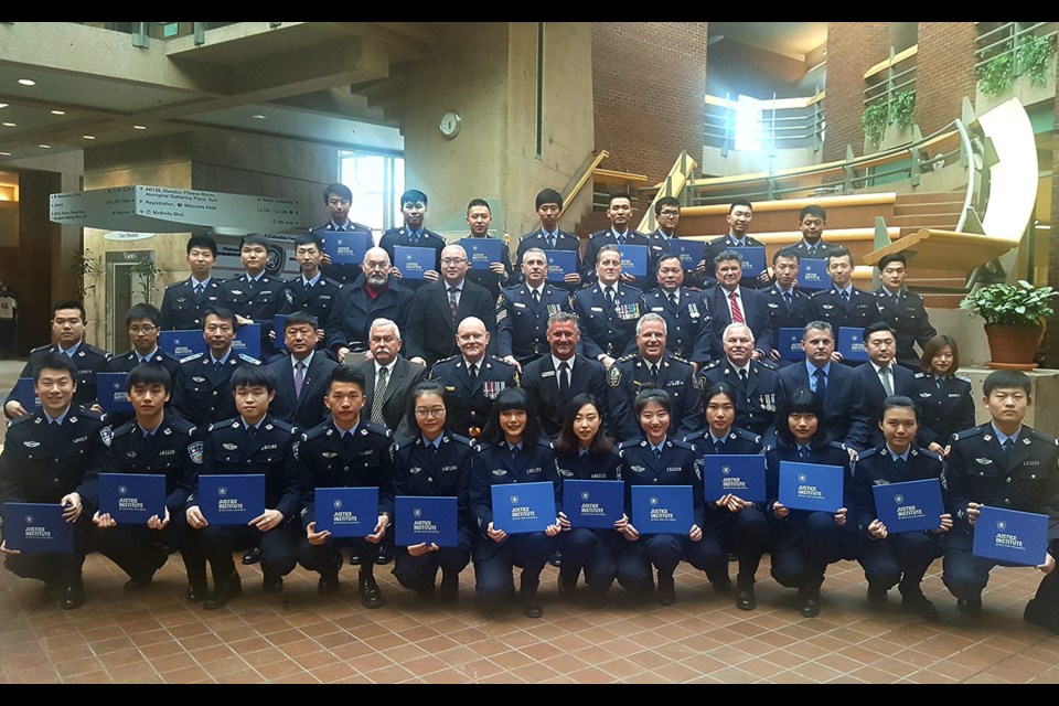 JIBC international students with VPD Chief Adam Palmer, sixth from left, and JIBC President Michel Tarko, sixth from right, in second row at a ILES graduation ceremony
