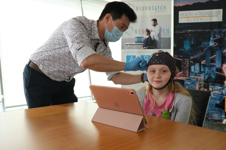 Sean Choi, kinesiologist and NeuroCatch clinician, helps attach the NeuroCatch brain function monitoring device to Addison Cox, 12. HEALTHTECH CONNEX