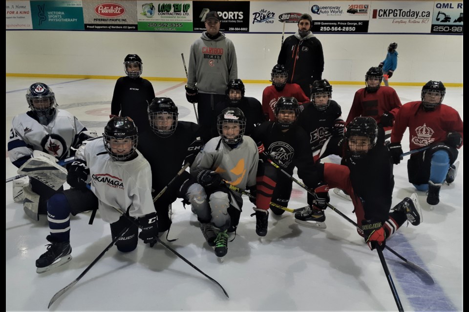 Kids in the U-13 division at the Northern Ice Sports multi-sport spring camp stretch out their muscles after a morning hockey skills workout with Ryan Howse, left, and Brandon Manning.