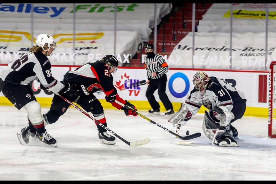 Cougars Craig Armstrong avoids the check of Vancouver Giants winger Justin Lies as he scores the go-ahead goal in the second period on goalie Trent Miner in Saturday's WHL game in Kamloops. The Cougars beat the Giants 6-3.