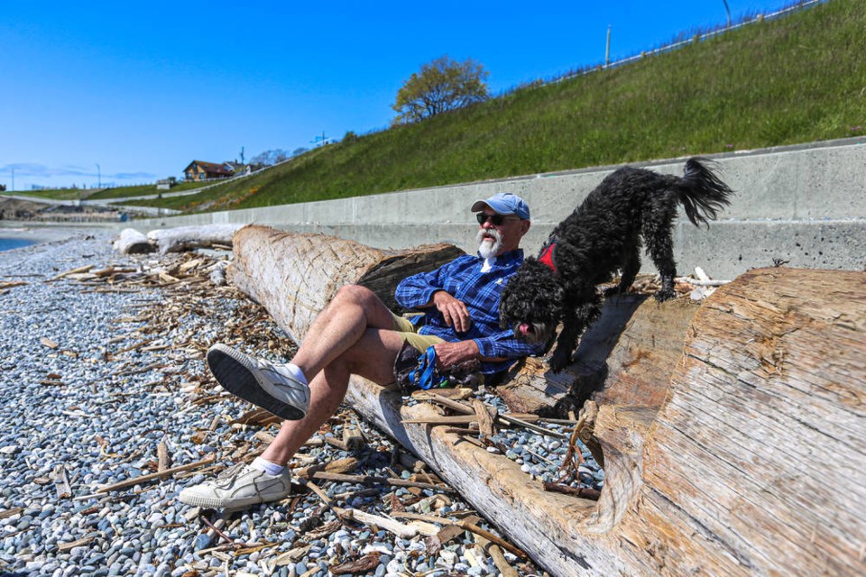 Robert Black and his dog, Jet, relax on a carved bench on Ross Bay Beach on Tuesday, May 4, 2021. ADRIAN LAM, TIMES COLONIST