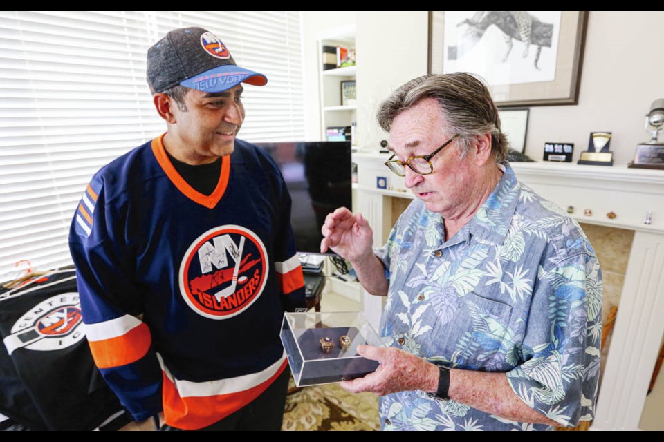 With NHL playoff excitement in the air, New York Islanders super fan and Victoria Police Chief Del Manak, left, and former broadcaster Tim Ryan look over the Islanders’ Stanley Cup rings that Ryan was given by the club. ADRIAN LAM, TIMES COLONIST