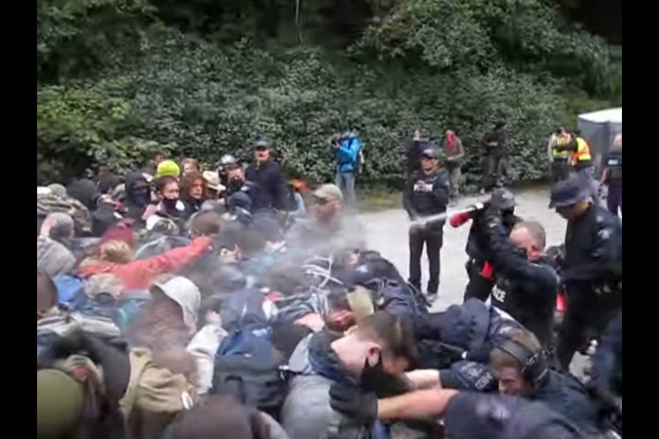 A screengrab from a video posted to YouTube on Saturday, Aug. 21, 2021, shows RCMP using pepper spray on a group of protesters at Fairy Creek.