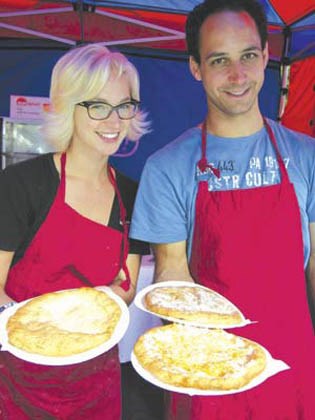 Ali Mass (left) and Lorant Jakab hold up some Hungarian pan-fried bread of different flavours under the Oven Monkey Bakery tent.