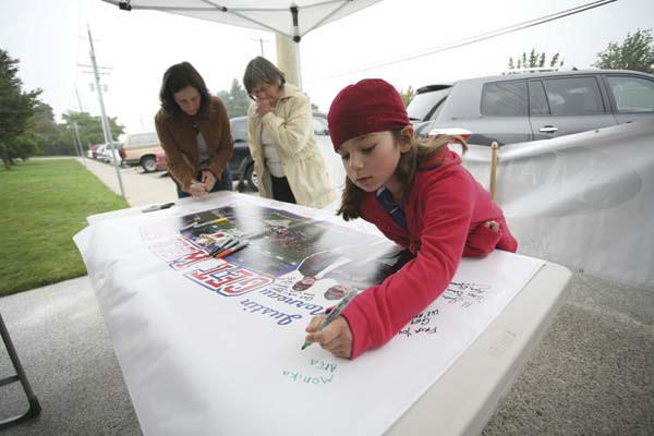 Monika Arcadi signs a banner on Saturday at Moody Park that New Westminster Baseball will be sending to injured Minnesota Twins first baseman Justin Morneau. Morneau has been injured for most of the past two seasons and local officials want to send their get well wishes to the Royal City product.