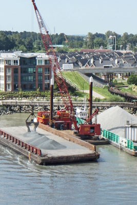 Cranes loaded onto barges begin removing the gravel Sunday so tugs can remove the barge lodged on the protection pier of Southern Railway of B.C.'s rail bridge.