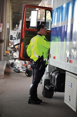 New Westminster Police Const. Jamie Crowston inspects a commercial truck on Front Street during a two-day blitz by law enforcement and provincial and federal safety officials. Investigators were making sure truckers had complete repair logs and were safely transporting their cargo through the city.
