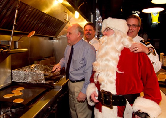From left, ceremonial pancake flippers Mayor Wayne Wright, fire chief Tim Armstrong, Santa and police chief Dave Jones at the Paddlewheeler Pub during the Christmas for Kids toy drive.
