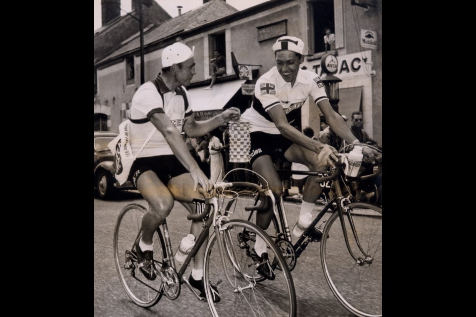 Tony Hoar, right, receives a paper lantern from Henri Sitek, who finished second to last, on the final day of the Tour de France in 1955.