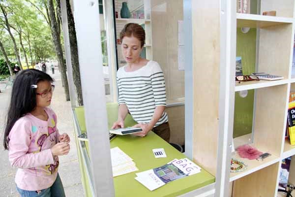 Stop and swap: Rebecca Bayer, right, makes a trade with Carmen Lee at the Give and Take kiosk at Burnaby Civic Square. Bayer's exhibition is part of an off-site art installation by the Burnaby Art Gallery, which will run at the square outside the Metrotown library branch all summer featuring a variety of artists.