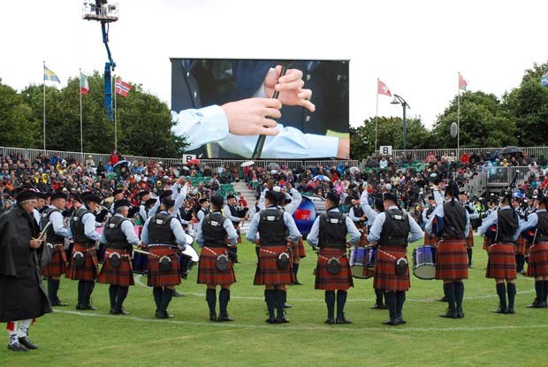 Blustery weather: Spectators' umbrellas start to go up as a wind and rainstorm hit the SFU Pipe Band at the world pipe band championships in Glasgow Sunday afternoon. Some umbrellas were blown inside-out as the weather hammered the band. At left, drumming judge Sandy Steele has a waterproof Inverness cape.
