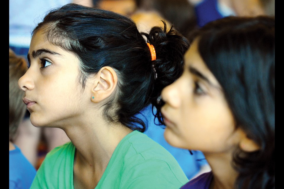 Nine-year-old twins Lilia and Parmida Zehtab listen to the story read by librarian David Milner.