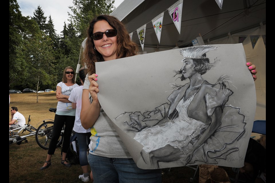 Michele Mateus displays some of the art given away at the Papergirl tent during Family Fun at the Arch this past Saturday.