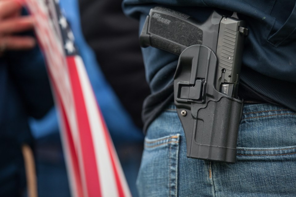 A demonstrator carries a handgun while listening to speakers at a pro-gun rally on January 19, 2013 in Olympia, Washington. The Guns Across America national campaign drew thousands of protesters to state capitols, including over 1,000 in Olympia, Washington.