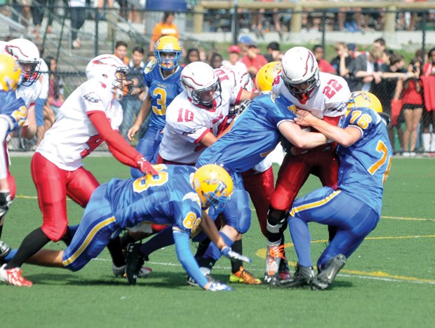 Carson Graham running back A.J. Blackwell protects the ball against a pair of Handsworth tacklers in the Buchanan Bowl played Saturday at Carson. Blackwell racked up 142 yards and two touchdowns to lead his Eagles to a 31-14 win. Photo Paul McGrath, North Shore News