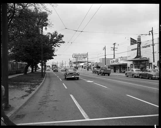 Street view of cars on Kingsway and Firestone neon sign, 1954.