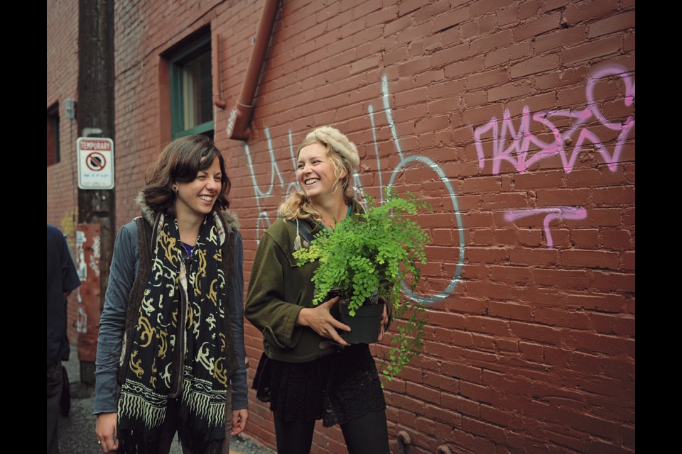 Friends Colby Ferguson (left) and Carly Woolner take home a plant bought from one of the vendors in the Livable Laneway market Sunday afternoon. The alley that runs from East 7th to Broadway Street, just west of Main Street, was turned into an European-style market complete with vendors selling everything from food to jewelry, and musical performances.