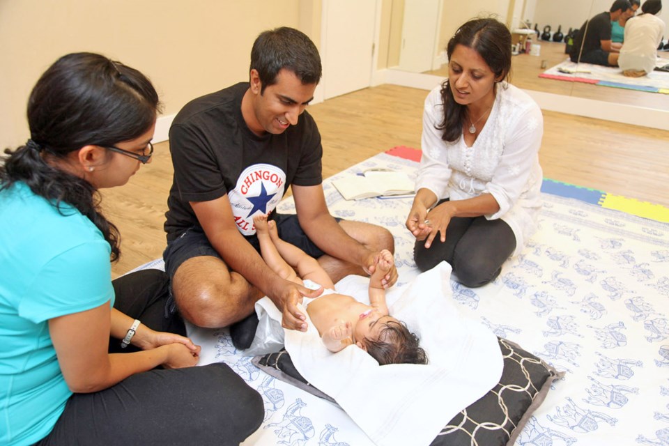 Parental bond: Babeeta Chhabra (right) guides parents Tina and Victor Jhingan through a baby massaging routine at her newly opened yoga studio, Nataraja Wellness Centre.