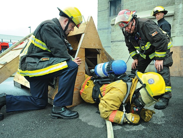 Reporter Brent Richter squeezes through a 16-inch gap at the Fire Ops 101 obstacle course.