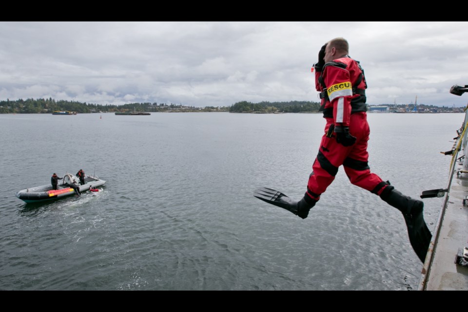 A diver jumps off HMCS Calgary during a simulated rescue, part of a submarine disaster drill on Wednesday, Oct. 2, 2013.