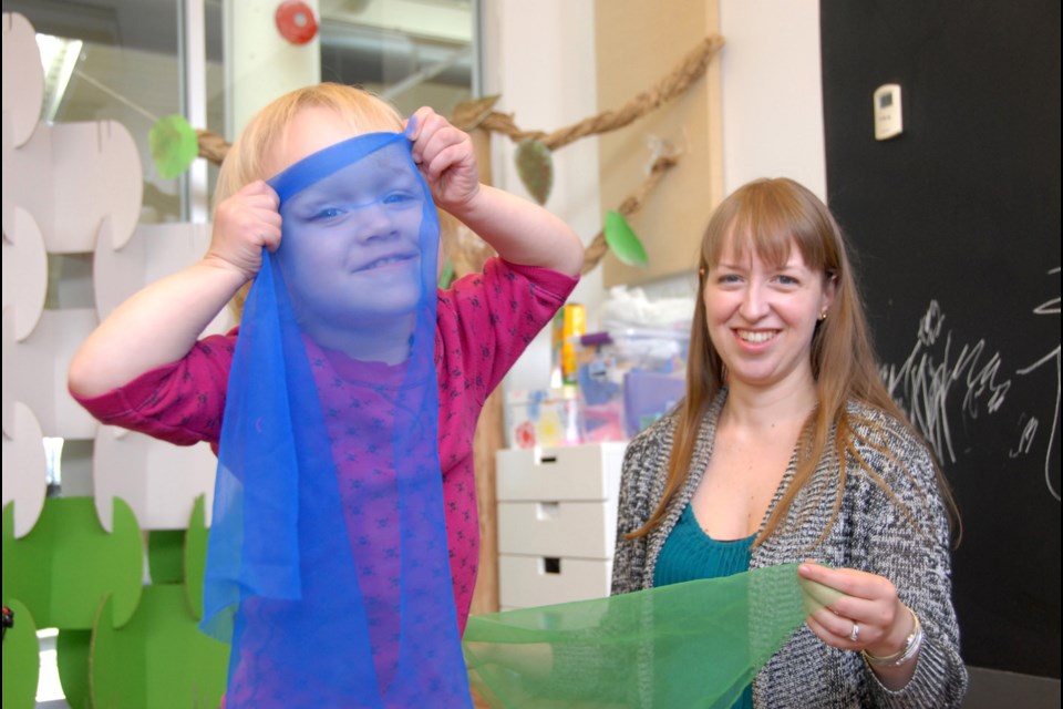 Peekaboo: Clara Fairbairn, almost two years old, plays with scarves at Music Box music school at River Market. She's with mom Vashti Fairbairn, who owns and operates the studio.