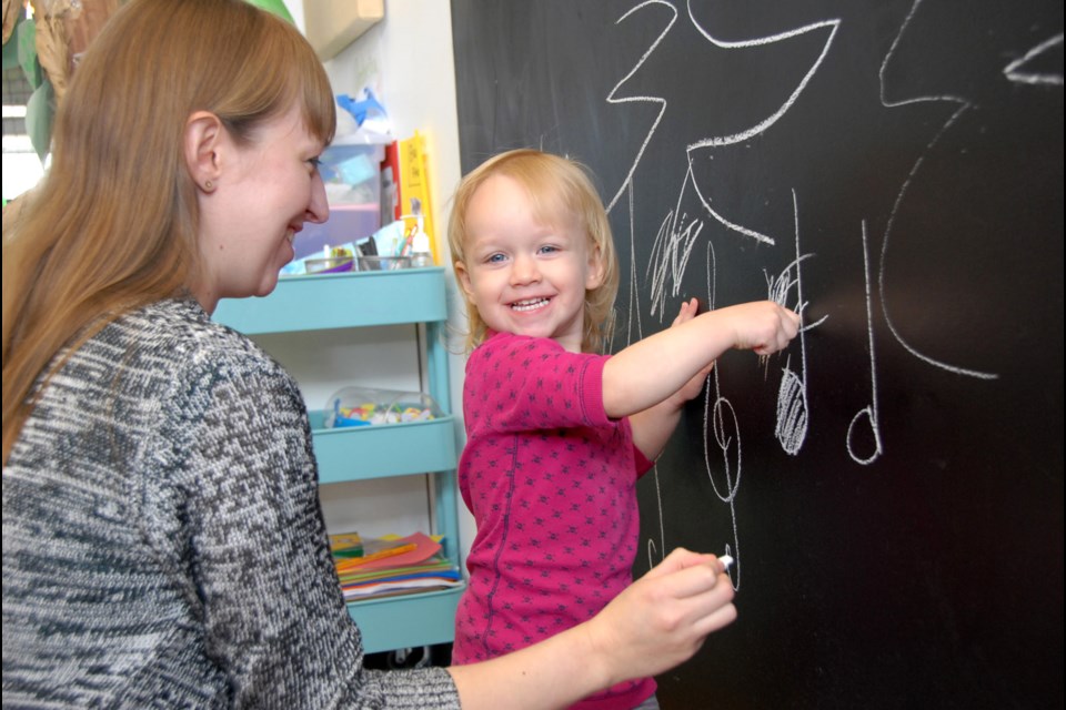 My turn: Clara Fairbairn, almost two years old, tries her hand at drawing music notes on the chalkboard at Music Box music school at River Market. She's with mom Vashti Fairbairn, who owns and operates the studio.