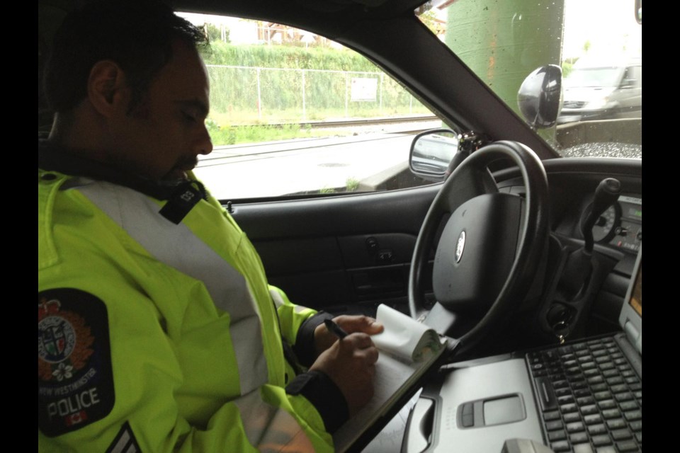 Ticket time: Sgt. Terry Dhut writes up a ticket for distracted driving. Talking, texting or using an electronic device while driving comes with a $167 ticket if and when police catch you.