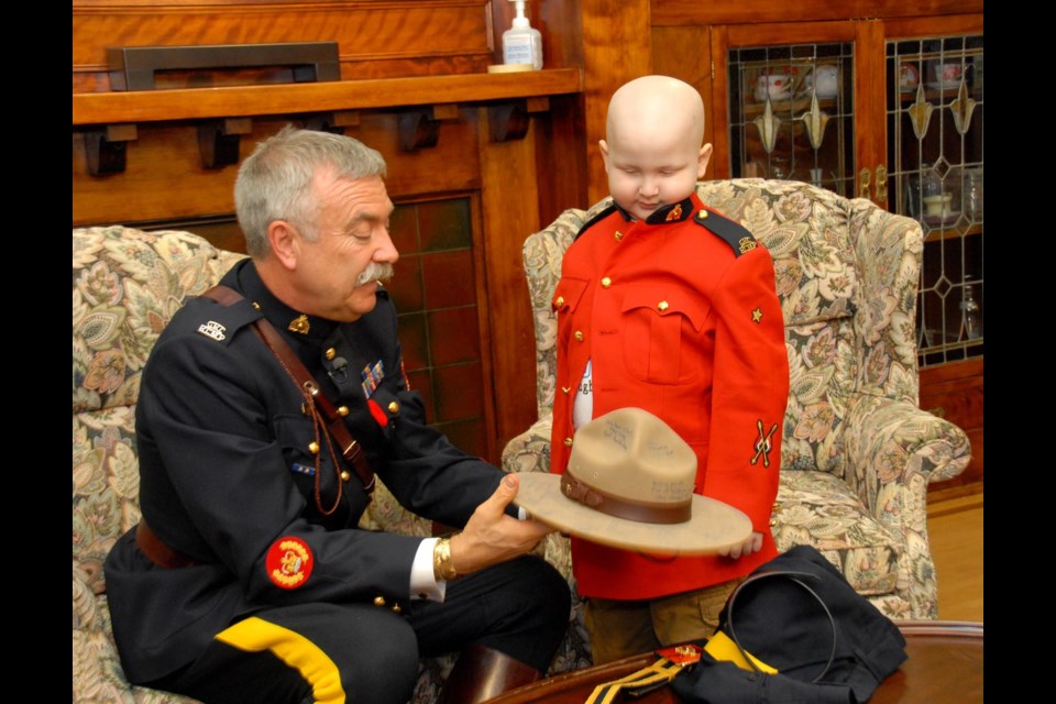 Inspection: From left, Burnaby RCMP Staff Sgt. Maj. John Buis shows Keian Blundell the official RCMP Stetson. Buis visited Keian at Canuck Place in Vancouver where he has been staying while he undergoes treatment for leukemia.